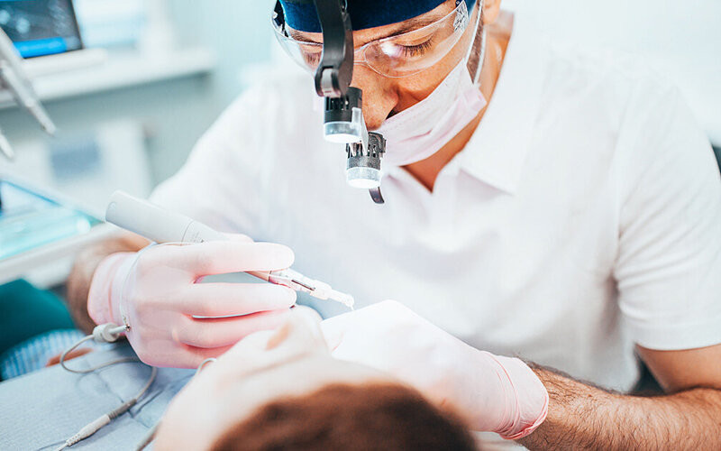 Ein Zahnarzt benutzt während einer Wurzelbehandlung ein zahntechnisches Instrument, um die Wurzelkanäle zu reinigen.