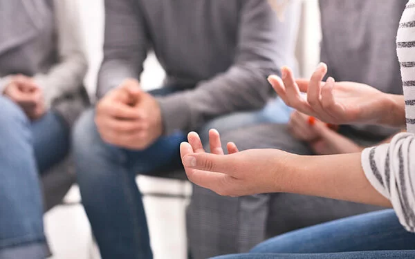 Frau erzählt ihre Geschichte in einer Selbsthilfegruppe; Nahaufnahme der gestikulierenden Hände.