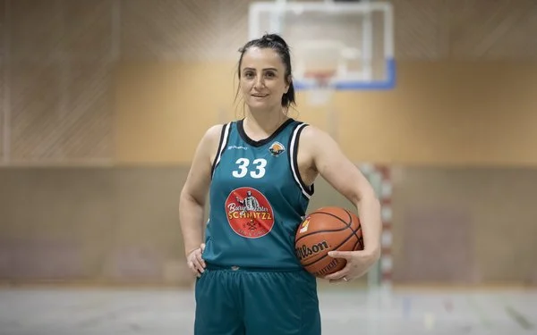 Lule Duriqi steht im Trikot in einer Sporthalle und hat einen Basketball und der Arm.
