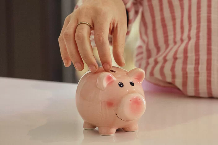 Eine Frau steckt Geld in ein Sparschwein.