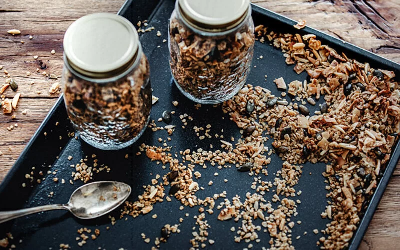 Selbst gebackenes Müsli auf einem Backblech und in Gläsern.