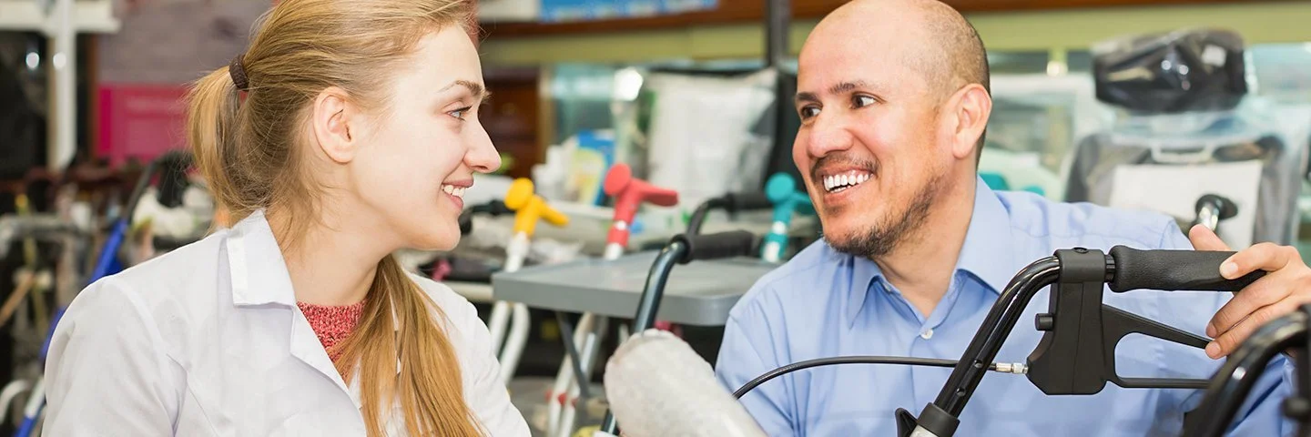 Eine Frau und ein Mann sind in einem Geschäft für Gehilfen und betrachten einen Rollstuhl.