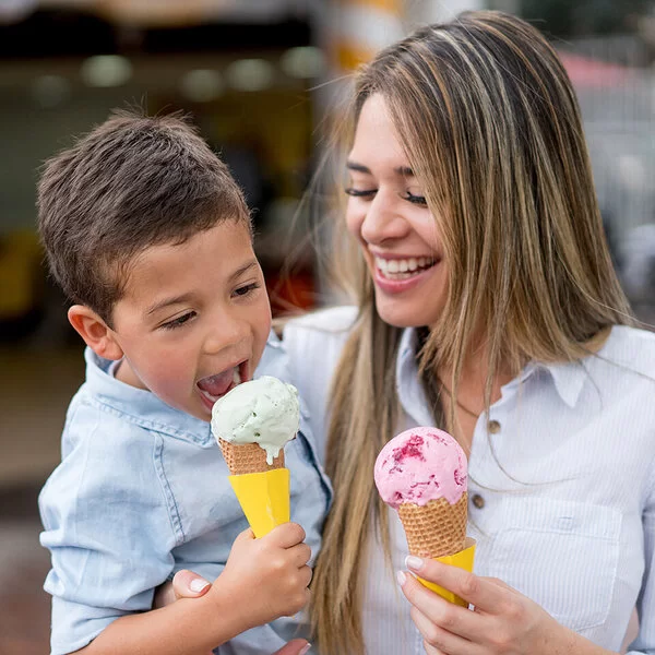 Eis aus der Eisdiele: Eine Mutter hat ihren Sohn auf dem Arm, beide essen eine Kugel in der Waffel.