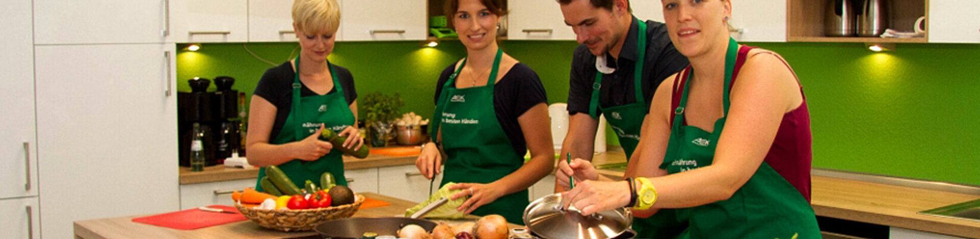 Drei Frauen und ein Mann kochen gemeinsam in einer Küche.