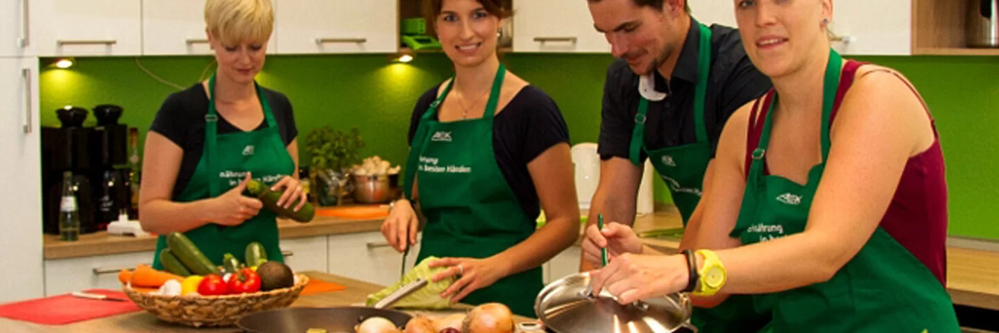 Drei Frauen und ein Mann kochen gemeinsam in einer Küche.