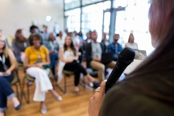 Ein Konferenzredner spricht vor einer Reihe Teilnehmer.