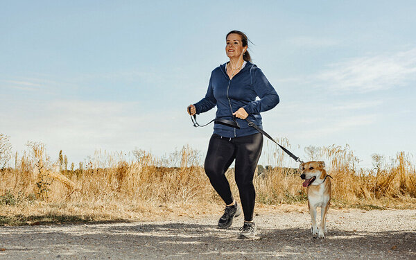 Vera joggt mit ihrem Hund an der Leine.