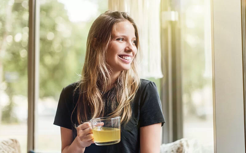 Eine Frau hält ein Glas mit Knoblauch-Zitronen-Kur in der Hand.