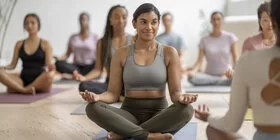 Eine junge Frau macht gemeinsam mit ihrer Sportgruppe Yoga.