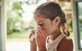 Kleines Mädchen hat Heuschnupfen und putzt sich die Nase.