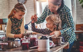 Frau kocht mit zwei kleinen Mädchen Marmelade ohne Zucker.