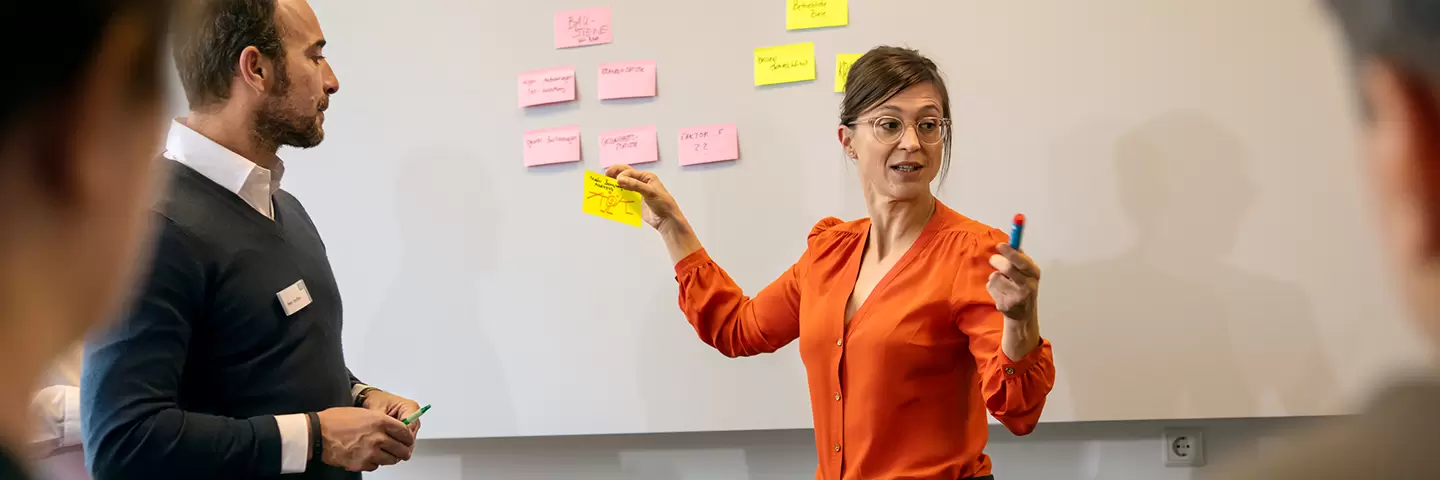 Eine Frau hält ein Post-It in der Hand.