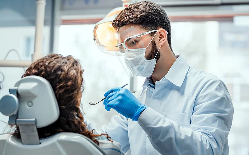 Ein Zahnarzt untersucht die möglichen Ursachen für den Mundgeruch einer Patientin.