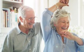 Älteres Paar tanzt lächelnd in der Küche