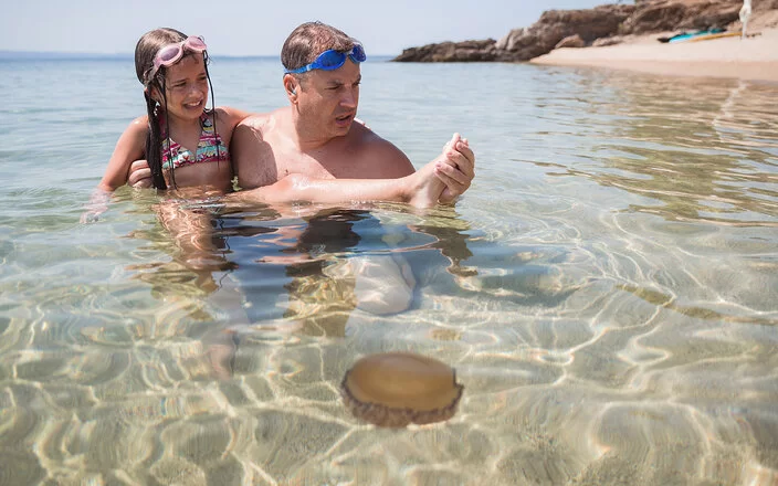 Vater hält seine Tochter im Arm, sie wurde im Wasser von einem Petermännchen gestochen.