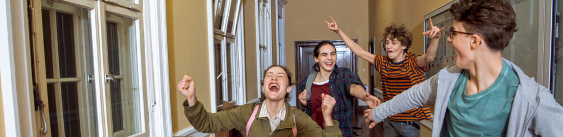 Vier Schüler laufen im Gang und jubeln.