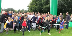Viele Kinder renen durch das Ziel bei einem Laufwettbewerb.