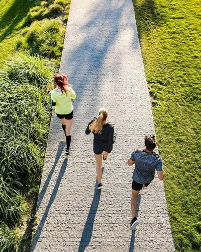 Drei junge Menschen beim Laufen im Park von hinten aus der Vogelperspektve aufgenommen.