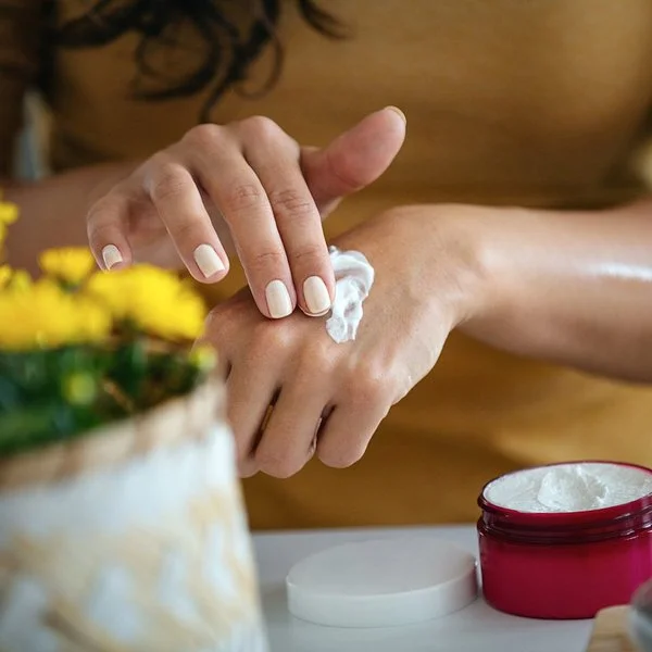 Eine Frau cremt sich die Hände mit einer selbstgemachten Handcreme ein.