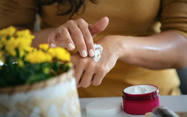 Eine Frau cremt sich die Hände mit einer selbstgemachten Handcreme ein.