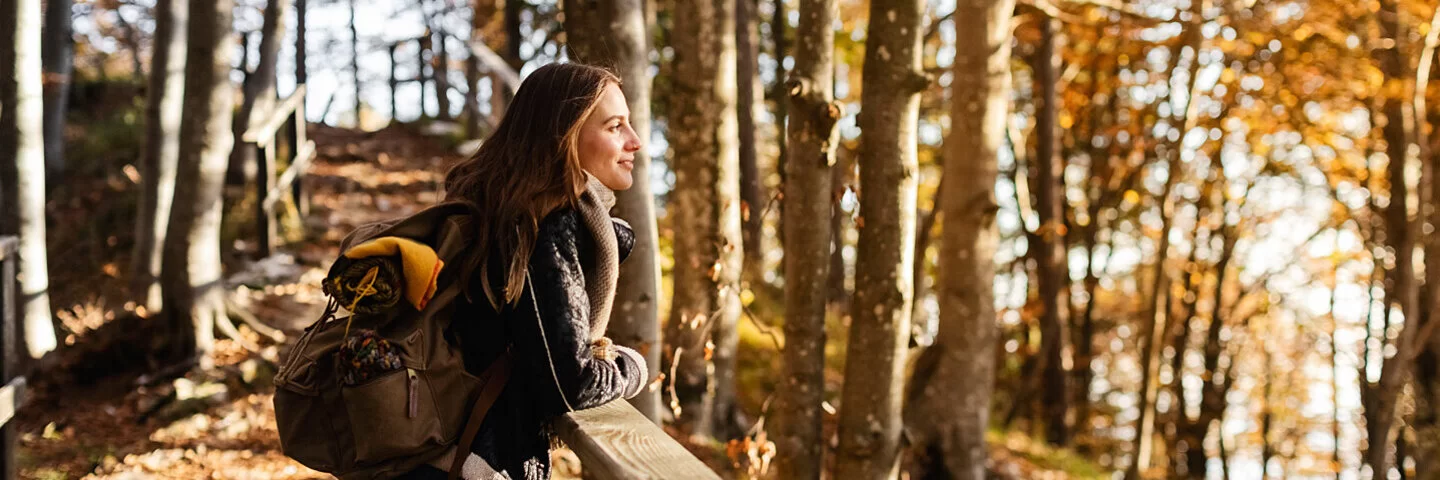 Eine junge Frau genießt das Alleinsein im Wald.