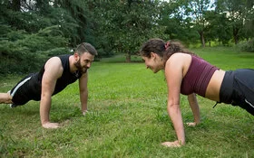 Ein junges Paar macht gemeinsam im Freien Functional Fitness.