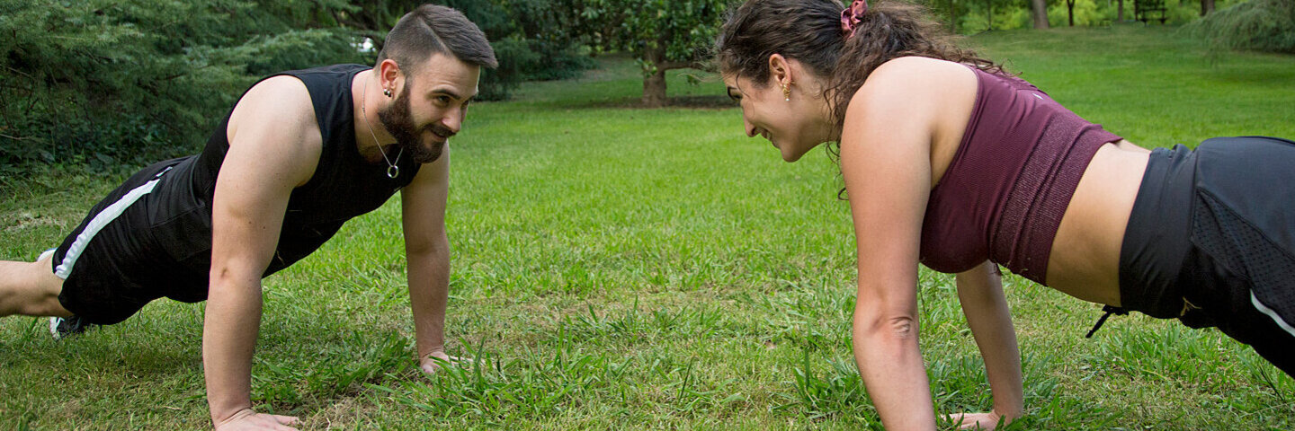Ein junges Paar macht gemeinsam im Freien Functional Fitness.