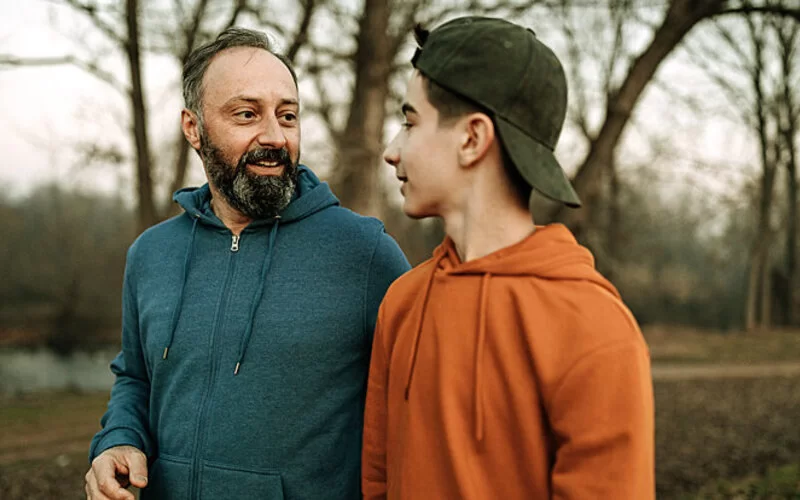 Ein Vater führt ein Vater-Sohn-Gespräch bei einem Spaziergang.