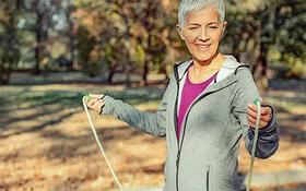 Eine Frau geht im Wald Seilspringen