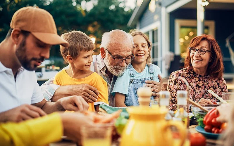 Eine glückliche Familie sitzt beim gemeinsamen Essen im Garten.