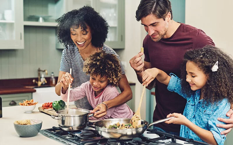 Eine Familie steht am Herd und kocht gemeinsam, um Demenz vorzubeugen.