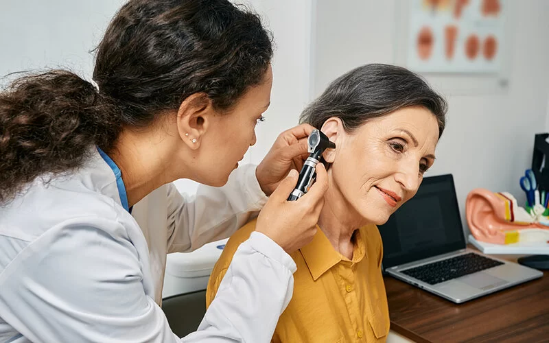 Eine HNO-Ärztin untersucht das Ohr einer Patientin mit Hörsturz.