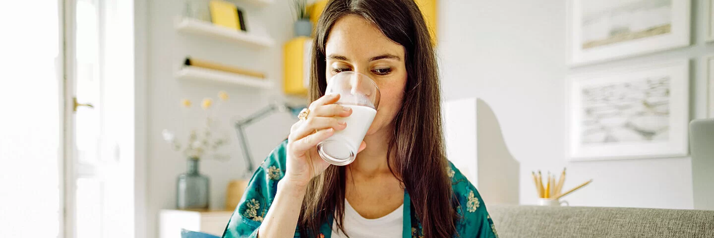 Eine junge Frau trinkt ein Glas Kefir.