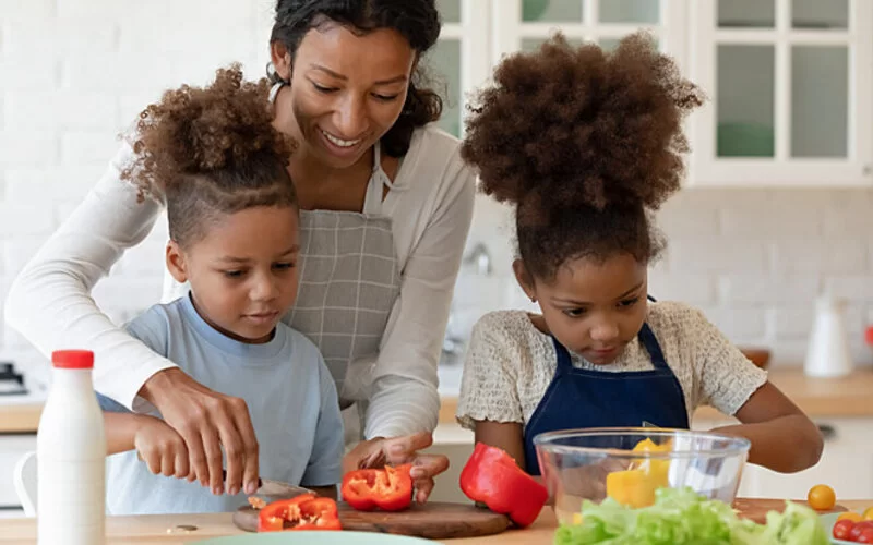 Eine Frau bereitet mir ihren beiden kleinen Kindern eine Mahlzeit in der Küche vor.