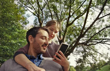 Eine Frau und ein Mann blicken auf ein Smartphone. Die Übertragung von Daten an die AOK erfolgt über eine Authentifizierung.