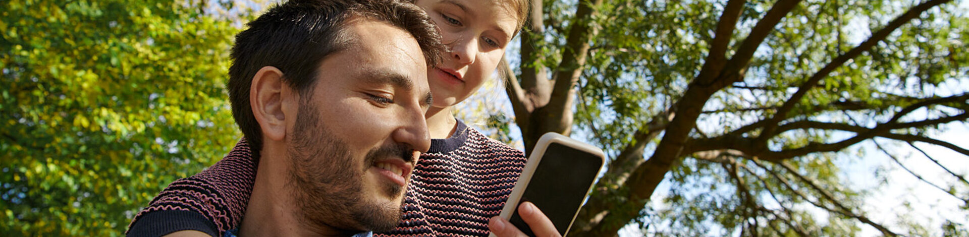 Eine Frau und ein Mann blicken auf ein Smartphone. Die Übertragung von Daten an die AOK erfolgt über eine Authentifizierung.