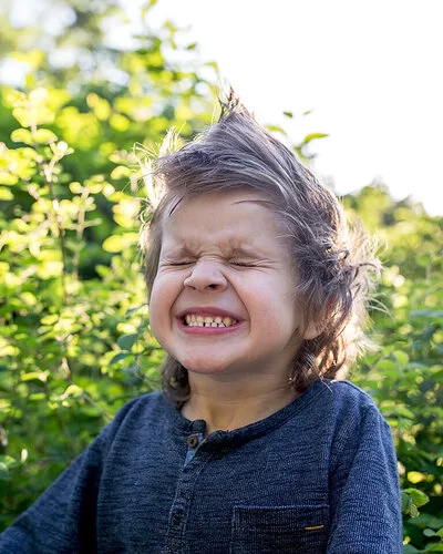 Ein kleiner Junge mit zusammengekniffenen Augen im Freien.