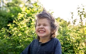 Ein kleiner Junge mit zusammengekniffenen Augen im Freien.