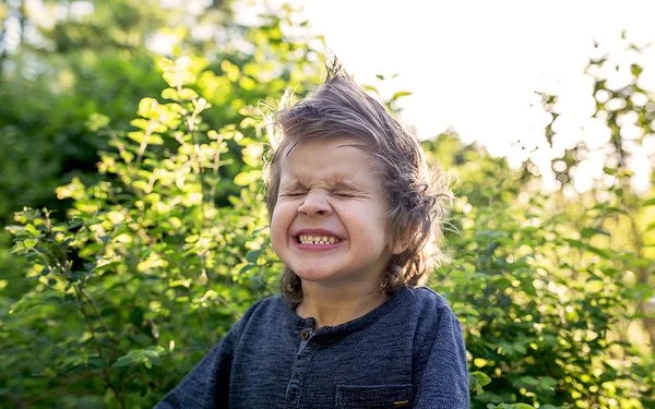 Ein kleiner Junge mit zusammengekniffenen Augen im Freien.