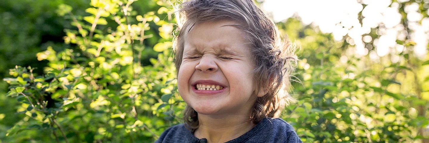 Ein kleiner Junge mit zusammengekniffenen Augen im Freien.