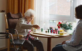 Frau im FSJ spielt mit einer älteren Dame eine Brettspiel.