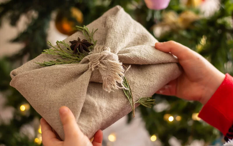 Ein in ein grobes Leinentuch verpacktes Geschenk, verziert mit einem Zweig und Sternanis.