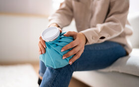Eine Frau kühlt ihr Knie mit einem Eispack.
