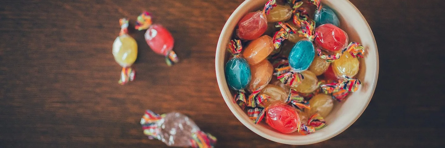 Eine Schüssel mit bunten Bonbons auf einem Holztisch