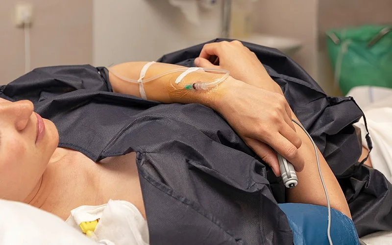 Eine Gebärende steuert die Schmerzmitteldosierung über eine Handpumpe selbst.