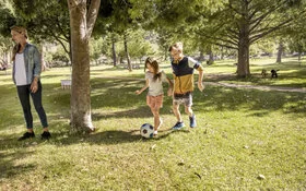 Mädchen und Junge spielen Fußball im Park. Mit dem AOK-Kinderbonus können sie bei der Teilnahme an Gesundheitskursen Punkte sammeln und eine Prämie erhalten.