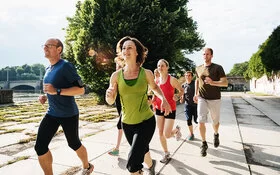 Frau macht Sport in einer Laufgruppe, um sich langfristig zum Sport zu motivieren.