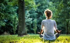 Eine junge Frau meditiert beim Waldbaden