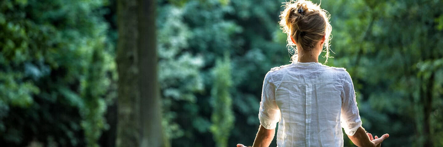 Eine junge Frau meditiert beim Waldbaden