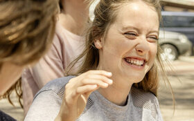 Teenagerin lacht beherzt mit ihren Freunden, weil sie weiß, Lachen ist gesund.